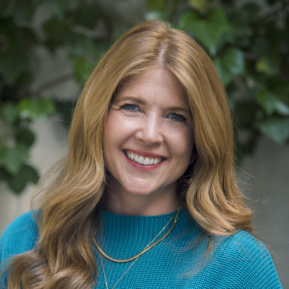 Jen Naecker is smiling in a warm outdoor setting.
